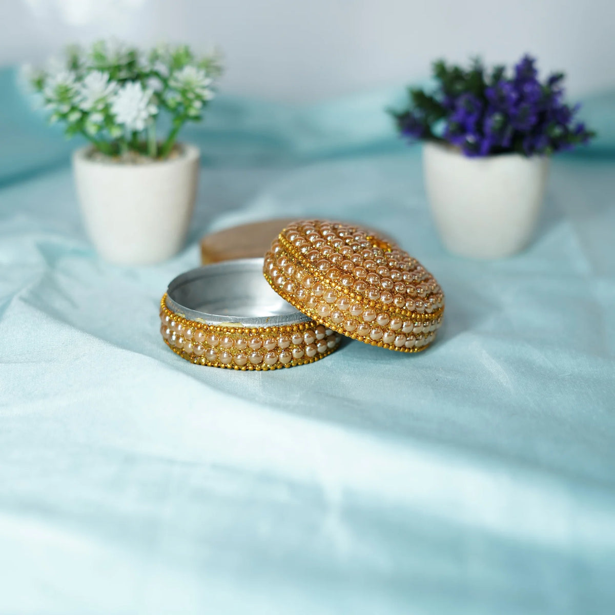 Open beaded pujan dibbi with its lid beside it, showing the silver-coloured metal lining
