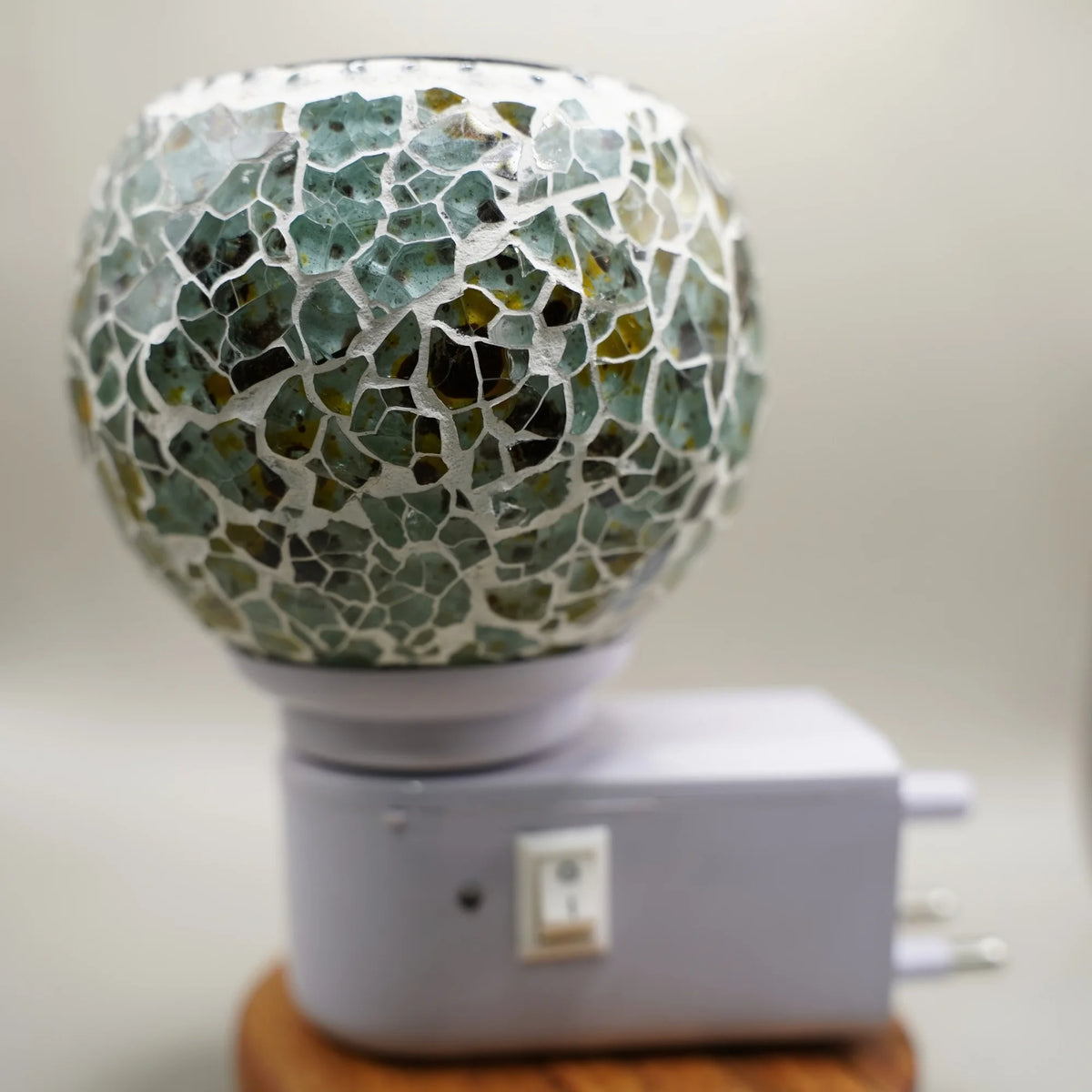 Electric kapoor dani with a green and amber mosaic glass bowl on a white plug-in base with an on and off switch