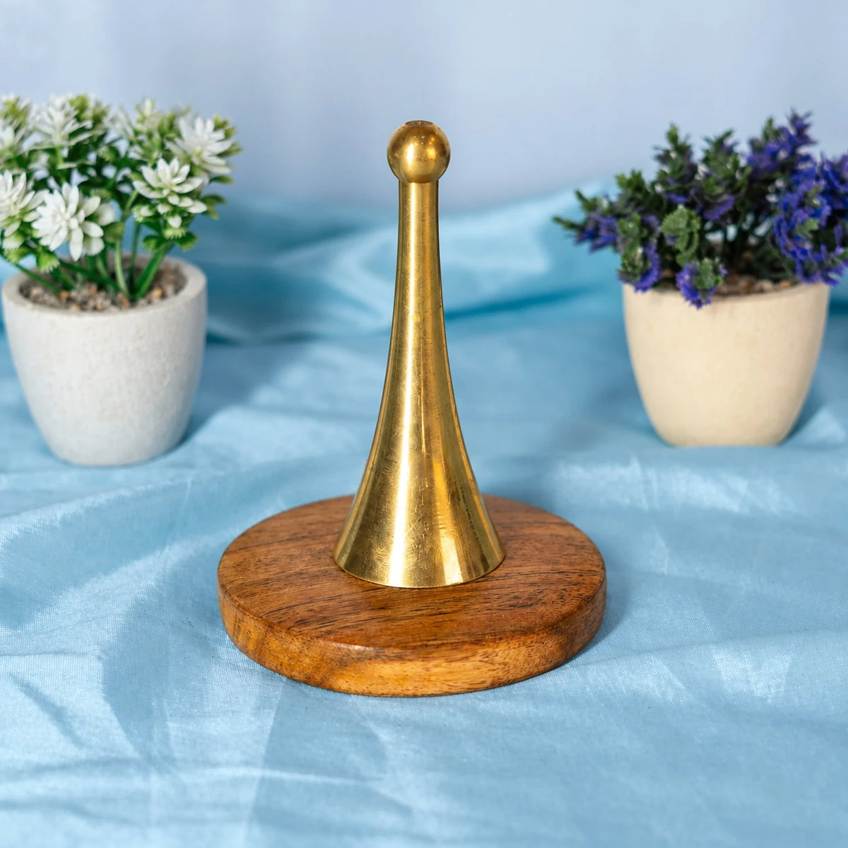 Plain polished golden brass hand bell with a slim tapering body and a ball top on a round wooden base