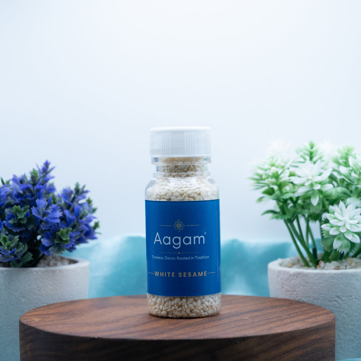 Aagam white sesame (safed til) seeds in a clear bottle with a blue label and white cap, shown on a wooden stand